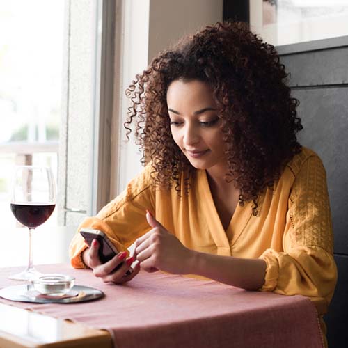 Woman sitting at a restaurant looking at her smartphone.